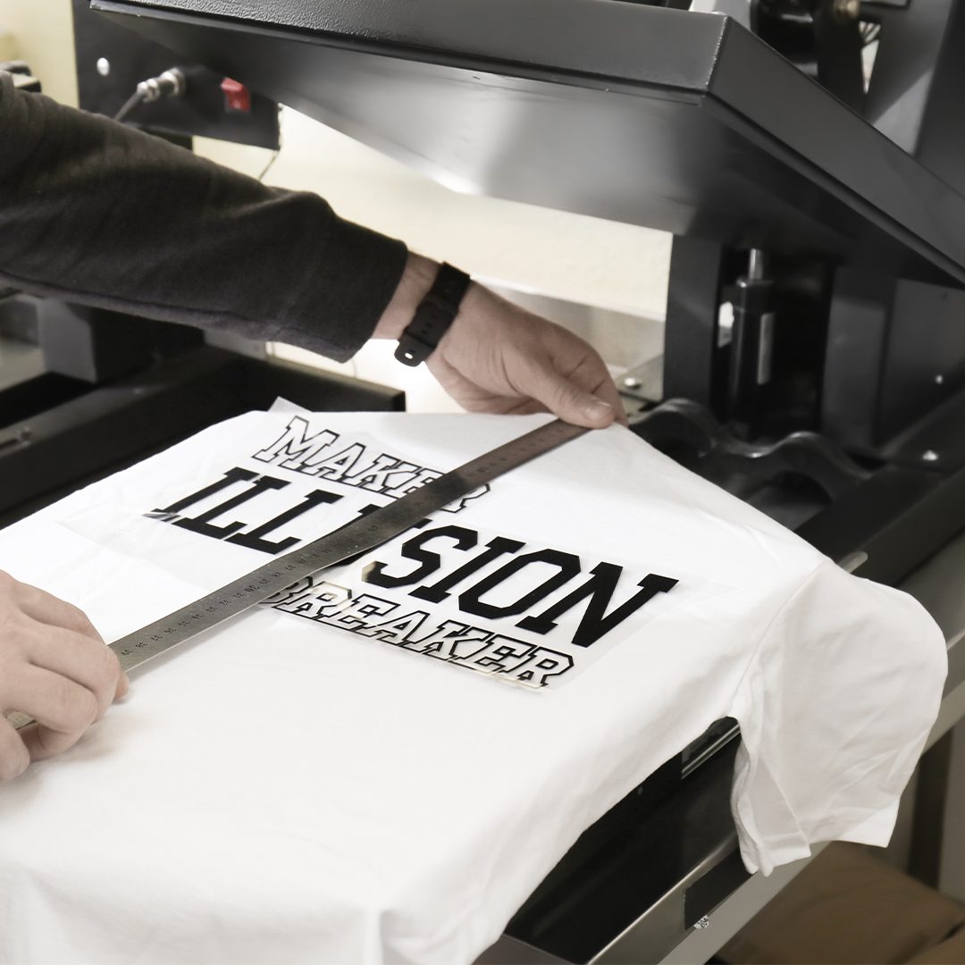 Young man printing on t-shirt at workshop